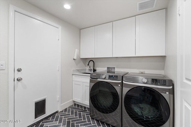 washroom with washing machine and clothes dryer, sink, and cabinets