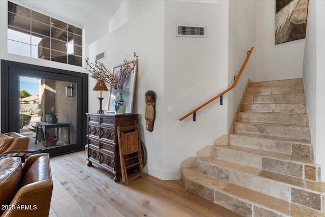 staircase featuring wood-type flooring and a high ceiling