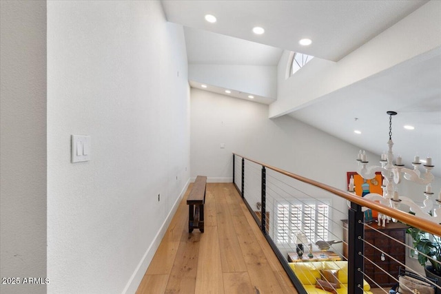 hallway with hardwood / wood-style floors, a notable chandelier, and a towering ceiling