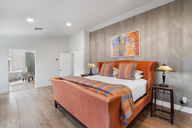 bedroom with connected bathroom and wood-type flooring