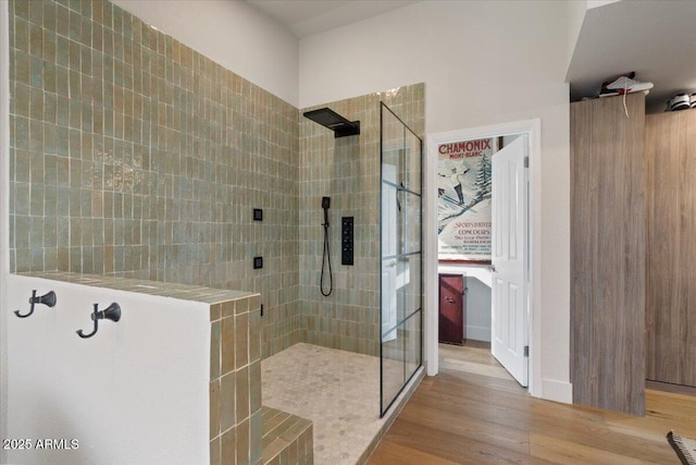 bathroom with a tile shower and wood-type flooring