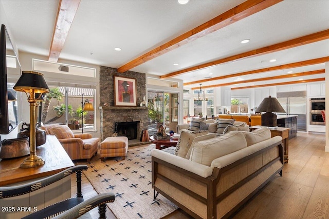 living room with a fireplace, beam ceiling, and light wood-type flooring