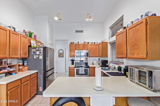 kitchen with stainless steel appliances, kitchen peninsula, a breakfast bar area, sink, and light tile patterned flooring