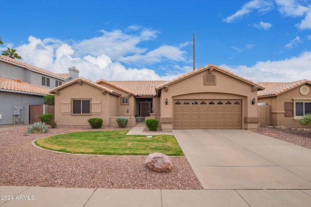 mediterranean / spanish home with concrete driveway, a tile roof, an attached garage, a front lawn, and stucco siding