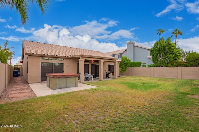 rear view of house with a yard, a hot tub, and a patio area