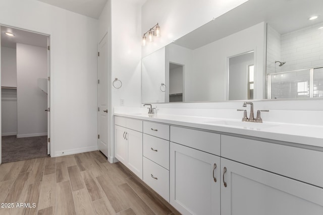 11660 W Luxton Ln, Avondale, AZ 85323 - bathroom featuring tiled shower, wood finished floors, double vanity, recessed lighting, and baseboards
