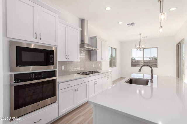 11660 W Luxton Ln, Avondale, AZ 85323 - kitchen with stainless steel appliances, a sink, wall chimney range hood, light countertops, and tasteful backsplash