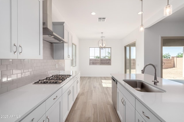 11660 W Luxton Ln, Avondale, AZ 85323 - kitchen featuring wall chimney range hood, stainless steel appliances, a sink, light wood-type flooring, and backsplash