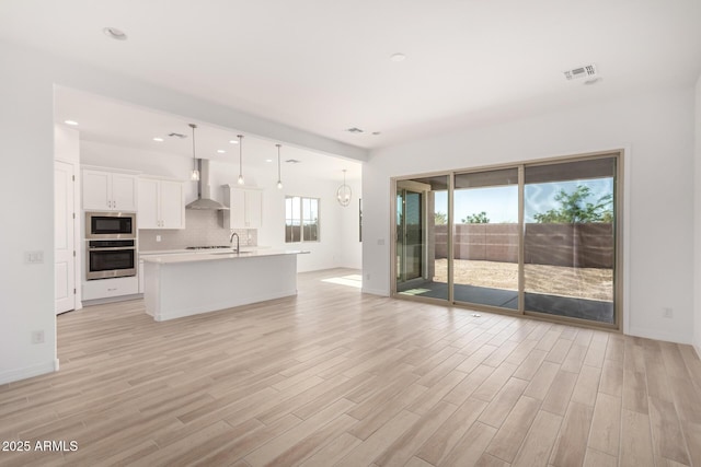 11660 W Luxton Ln, Avondale, AZ 85323 - unfurnished living room with light wood-style floors, baseboards, recessed lighting, and a sink