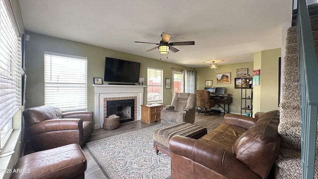 living room featuring ceiling fan, a brick fireplace, and light hardwood / wood-style floors