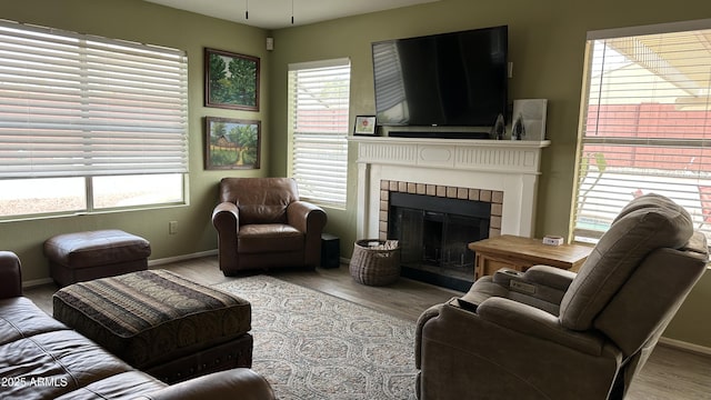 living room featuring a tiled fireplace and light hardwood / wood-style floors