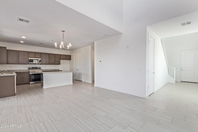 kitchen featuring pendant lighting, a center island, an inviting chandelier, stove, and sink