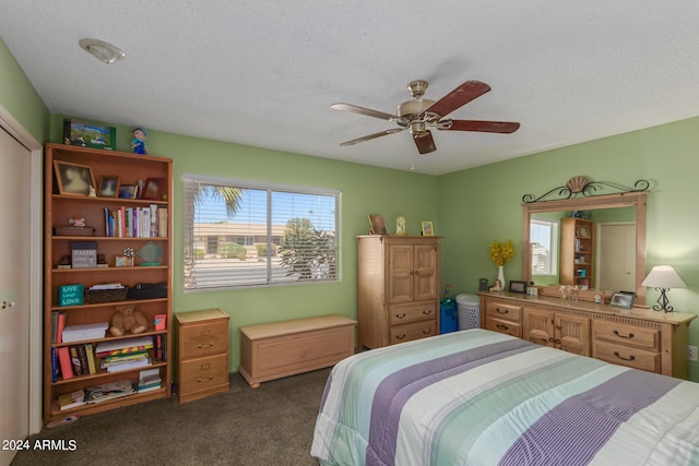 bedroom featuring dark colored carpet, ceiling fan, and a textured ceiling