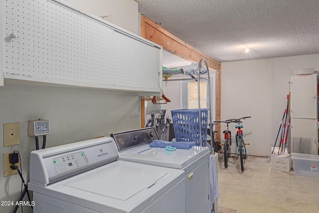 laundry room with cabinets, a textured ceiling, and independent washer and dryer