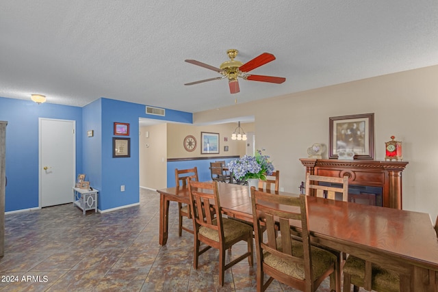 dining space with ceiling fan with notable chandelier and a textured ceiling