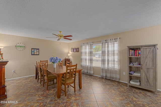 dining room featuring dark tile patterned flooring, ceiling fan, and a textured ceiling