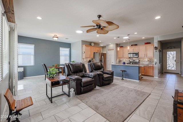 living room with ceiling fan, sink, and light tile patterned floors