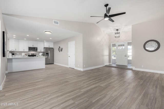 unfurnished living room with vaulted ceiling, ceiling fan, and light hardwood / wood-style floors