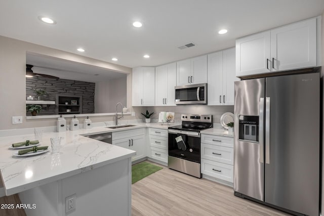 kitchen with sink, white cabinets, appliances with stainless steel finishes, and kitchen peninsula