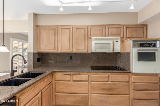 kitchen featuring pendant lighting, decorative backsplash, a sink, dark stone counters, and white appliances