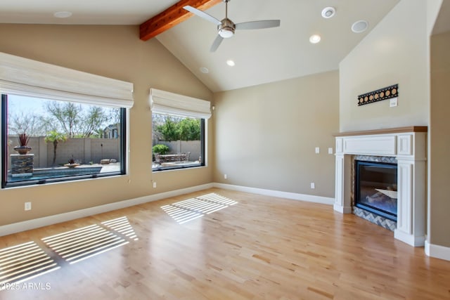 unfurnished living room with baseboards, a premium fireplace, high vaulted ceiling, light wood-style flooring, and beamed ceiling