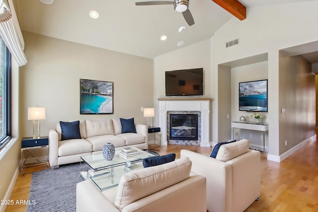 living room featuring visible vents, baseboards, light wood-type flooring, lofted ceiling with beams, and a premium fireplace