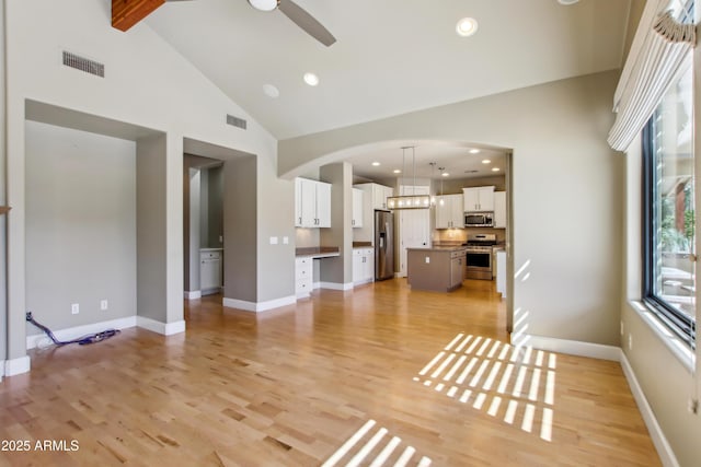 unfurnished living room with ceiling fan, visible vents, high vaulted ceiling, and light wood-style flooring