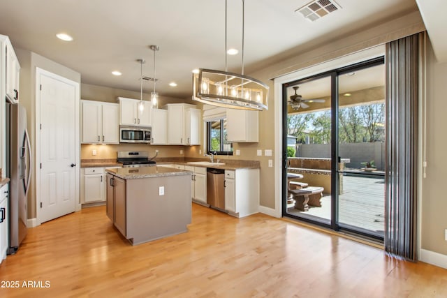 kitchen with visible vents, light wood-type flooring, a sink, a center island, and appliances with stainless steel finishes