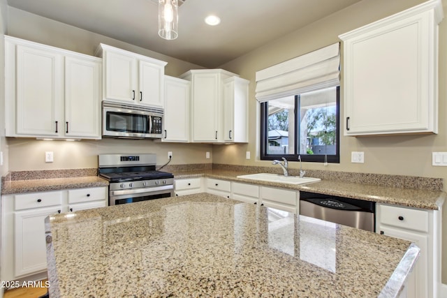 kitchen featuring a sink, stainless steel appliances, light stone countertops, and white cabinets