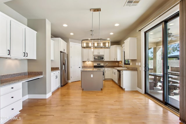 kitchen featuring visible vents, a center island, appliances with stainless steel finishes, built in study area, and a sink