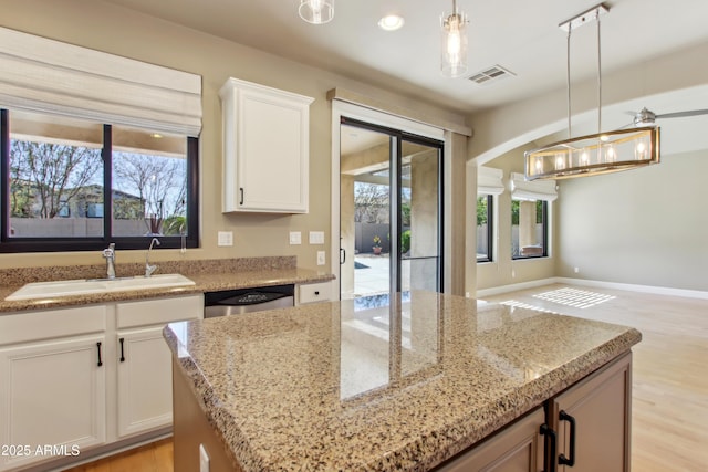 kitchen with dishwasher, light stone counters, a wealth of natural light, and a sink