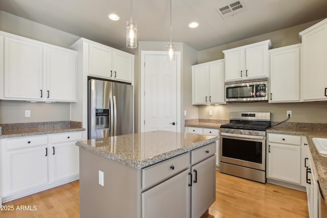 kitchen with a kitchen island, white cabinets, stainless steel appliances, and light wood-type flooring