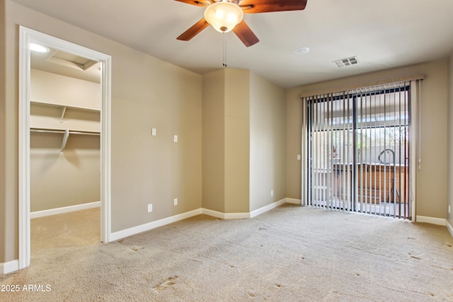 carpeted empty room featuring attic access, baseboards, visible vents, and ceiling fan