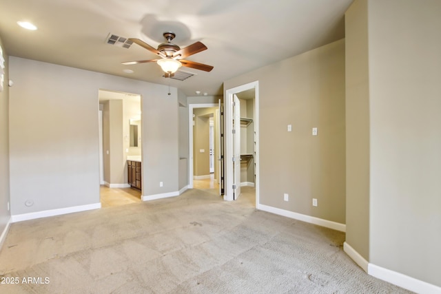 unfurnished bedroom featuring visible vents, baseboards, light carpet, and a spacious closet