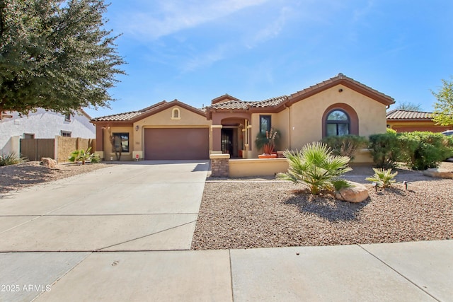 mediterranean / spanish house featuring stucco siding, a garage, driveway, and a tiled roof