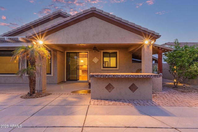 view of front of home with a tiled roof, stucco siding, ceiling fan, and a patio area