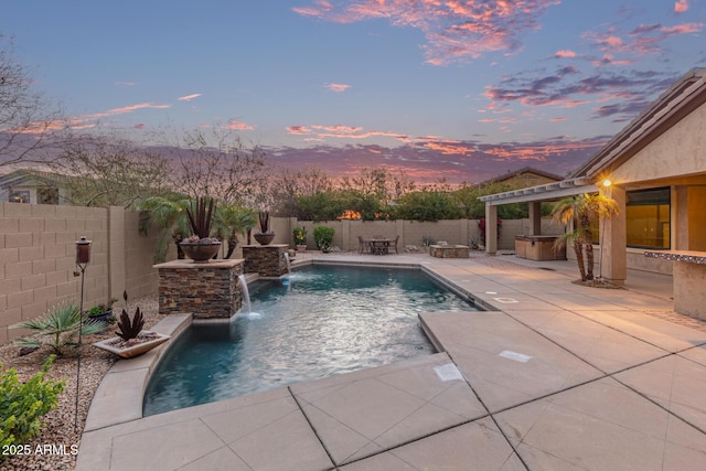 pool at dusk with a patio area, a fenced in pool, a hot tub, and a fenced backyard