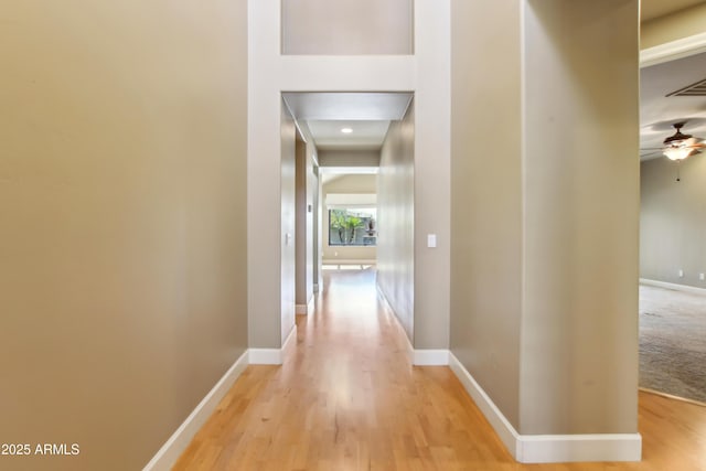 hallway featuring visible vents, light wood-style floors, and baseboards