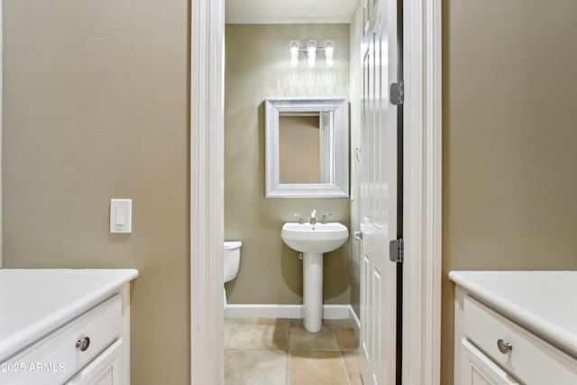 half bath featuring tile patterned floors, toilet, baseboards, and a sink