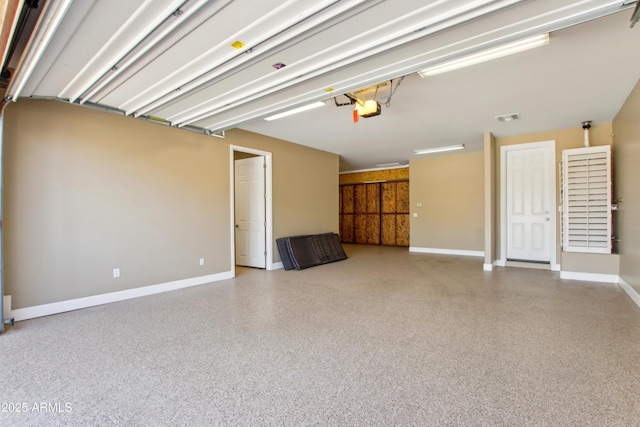 garage featuring visible vents, baseboards, and a garage door opener