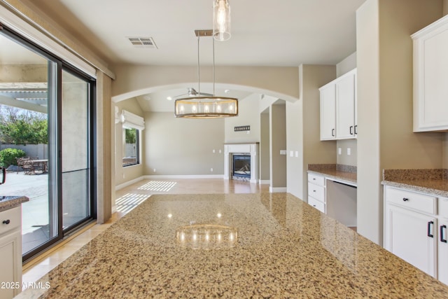 kitchen featuring visible vents, light stone countertops, white cabinets, and a fireplace