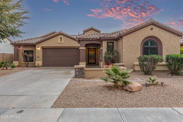 mediterranean / spanish-style house featuring stucco siding, a garage, concrete driveway, and a tile roof