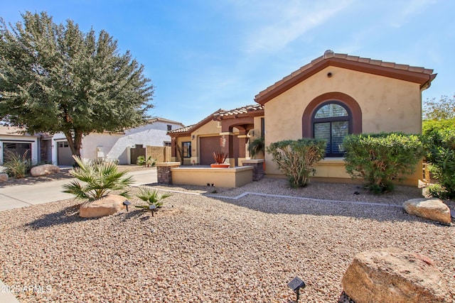 mediterranean / spanish house with stucco siding, fence, and a tiled roof