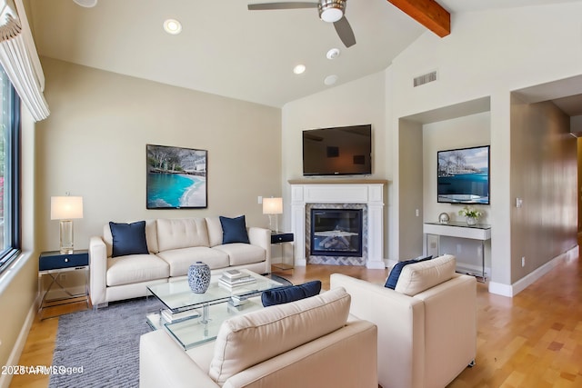 living room featuring visible vents, vaulted ceiling with beams, baseboards, a premium fireplace, and light wood-style flooring