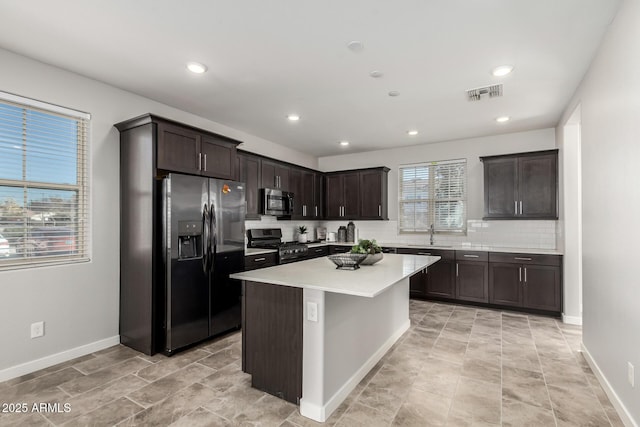 kitchen featuring a center island, sink, tasteful backsplash, dark brown cabinets, and stainless steel appliances