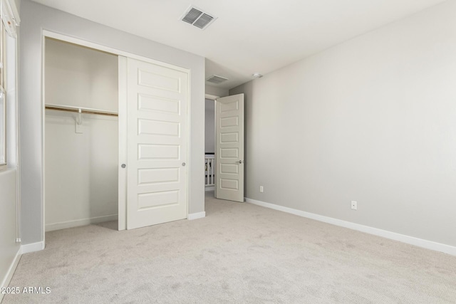 unfurnished bedroom featuring light carpet and a closet