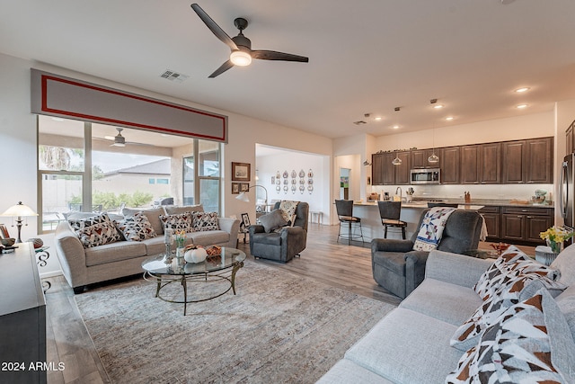 living room featuring sink, light hardwood / wood-style flooring, and ceiling fan