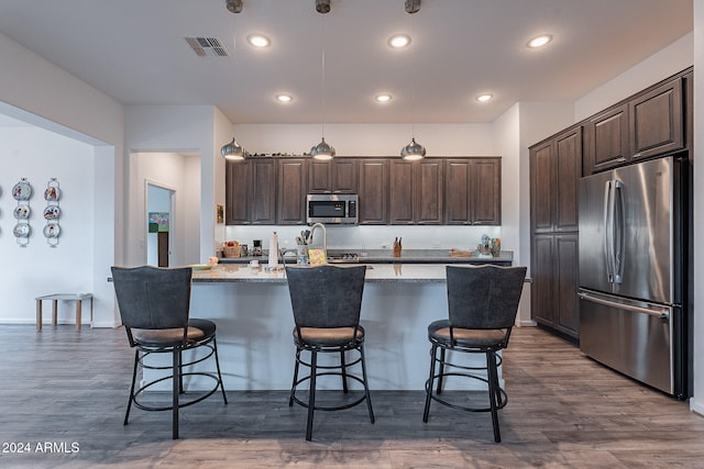 kitchen featuring appliances with stainless steel finishes, a breakfast bar, pendant lighting, and an island with sink