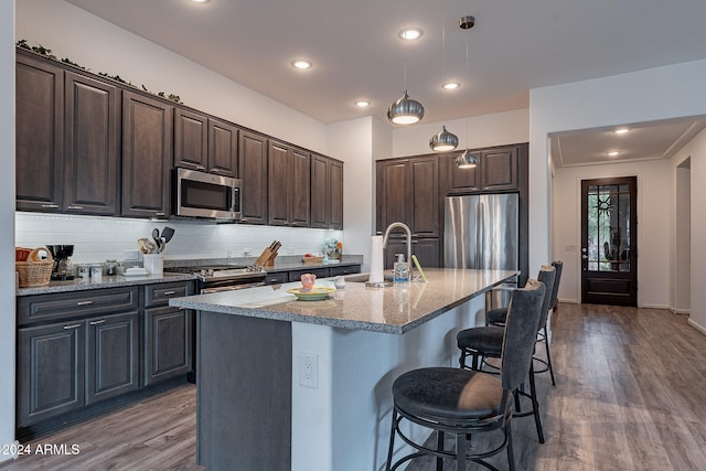 kitchen with decorative backsplash, hardwood / wood-style flooring, stainless steel appliances, a center island with sink, and sink