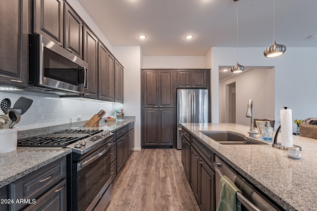 kitchen with stainless steel appliances, dark brown cabinets, light wood-type flooring, and hanging light fixtures